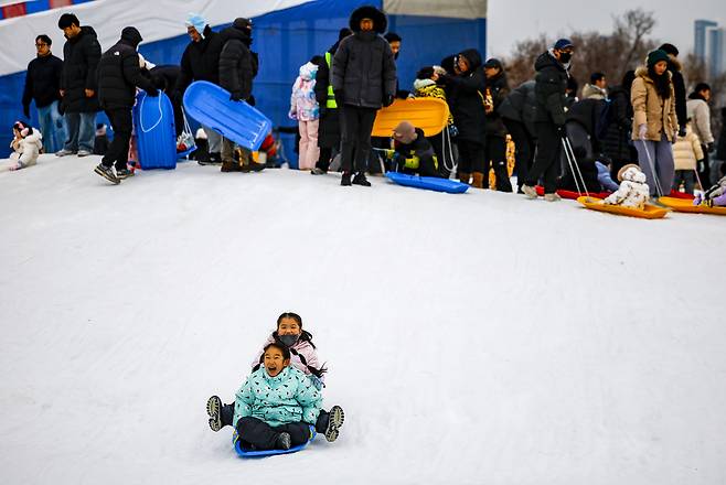 Citizens and children enjoy time at a snow sledding hill in Yeouido Hangang Park in Seoul on Sunday. (Newsis)
