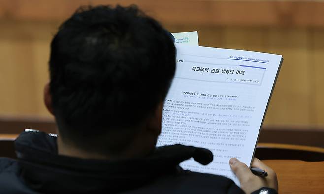 학교폭력 전담 조사관 역량강화 연수 개회식에서 한 조사관이 안내 책자를 읽고 있다. 연합뉴스