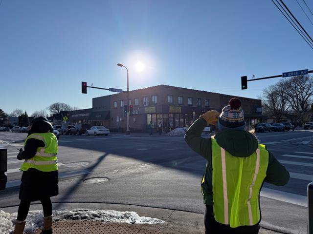 'ICE 감시단'을 자처한 학부모들이 14일 미 미네소타주 미니애폴리스의 한 공립학교 사거리에서 형광조끼를 입고 쉼 없이 주변을 살피고 있다. 최근 ICE는 이곳에서 자녀의 하교를 기다리는 학부모를 붙잡아갔다. 미니애폴리스=박지연 특파원