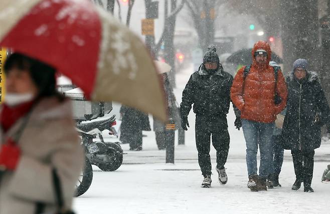 지난 12일 서울 종로구 종각역 인근에서 시민들이 눈을 맞으며 이동하고 있다. [연합뉴스]