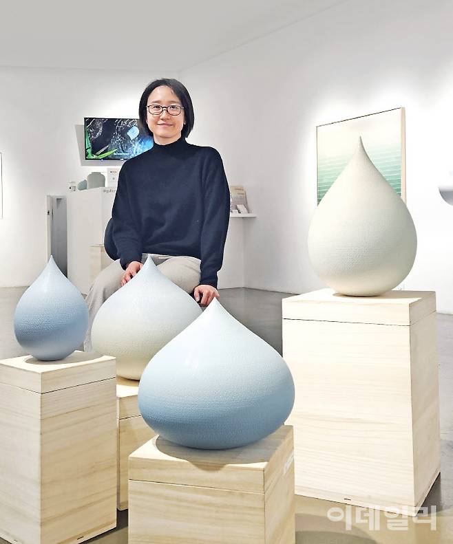 작가 조원재가 서울 용산구 이태원로 갤러리조은에서 성연화와 열고 있는 2인전 ‘평온의 가장자리’에 내놓은 자신의 작품들 곁에 앉았다. ‘푸른 물방울 ＃015-2’(2025, 18×18×25㎝·왼쪽) 옆으로 ‘순간의 가장자리’(2025) 연작이 옹기종기 모였다. 작가는 물레에 올린 점토로 물방울 모양의 ‘흙방울’을 빚는다. 은근한 색과 부드러운 외양에 감춘 속 깊은 단단함이 특별하다. 작가는 “물레의 원심력과 손에 맞물려 호흡하는 흙을 느끼며 순환하는 자연을 떠올리고 그 안에서 순간의 형상을 탐색한다”고 했다(사진=오현주 문화전문기자).