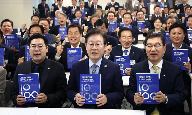 지난 2024년 당시 이재명 더불어민주당 대표와 박찬대 원내대표 등이 서울 여의도 중앙당사에서 열린 더불어민주당 기초자치단체장 교육연수에서 지방정부 기본사회 정책 사례가 담긴 책을 들고 기념촬영을 하고 있다. /뉴스1