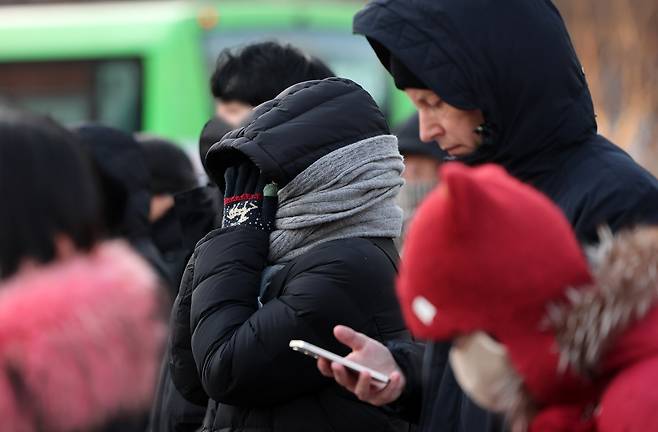 Pedestrians bundled up in thick clothes wait to cross the Gwanghwamun intersection in central Seoul on Jan. 20. [NEWS1]