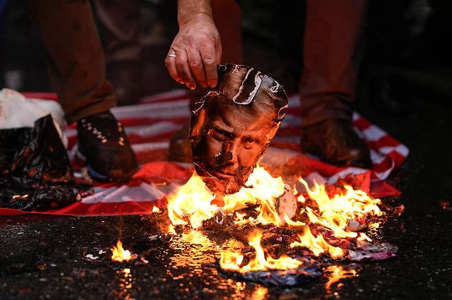 [이스탄불=AP/뉴시스] 18일(현지 시간) 튀르키예 이스탄불에서 이란 정부를 지지하는 시위대가 미국 국기와 도널드 트럼프 대통령 사진을 불태우고 있다. 2026.01.20.