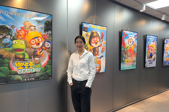 Woo Jee-hee, CEO of OCON, poses with posters for the “Pororo” animated film displayed at the company’s office in Seongnam, Gyeonggi Province, in December 2025. (OCON)