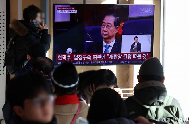 [서울=뉴시스] 조성우 기자 = 한덕수 전 국무총리의 내란 우두머리 방조, 내란 중요임무 종사 혐의 사건 1심 선고 재판이 열린 21일 오후 서울역 대합실에서 시민들이 한 전 총리의 1심 징역 23년 선고 관련 뉴스를 시청하고 있다. 2026.01.21. xconfind@newsis.com /사진=조성우