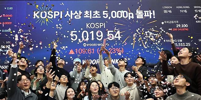 코스피가 장중 사상 처음으로 5,000선을 돌파하며 한국 증시가 새로운 전환점을 맞았으나 광주·전남 상장사들의 주가는 뚜렷한 반등세를 보이지 못하고 있다. 사진은 코스피 지수가 장중 사상 처음으로 5,019.54를 기록한 22일 서울 중구 우리은행 본점 딜링룸에서 딜러들이 코스피 지수 5,000선 돌파를 축하하고 있는 모습. /연합뉴스