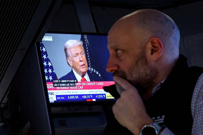 21일(현지시간) 미국 뉴욕시 뉴욕증권거래소(NYSE)에서 한 트레이더가 업무를 보는 가운데, 스위스 다보스에서 열린 세계경제포럼(WEF) 회의에서 도널드 트럼프 미국 대통령이 CNBC와 인터뷰하는 모습이 화면에 비춰지고 있다. (뉴욕/로이터연합뉴스)