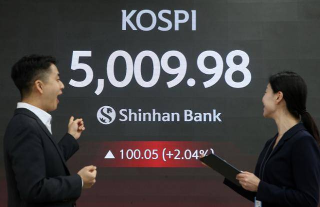 코스피가 장중 5,000을 넘어선 가운데 22일 서울 중구 신한은행 본점 로비에서 딜러들이 미소 짓고 있다. 연합뉴스