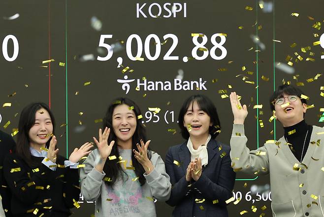 Traders cheer the benchmark Kospi surpasing the 5,000-point mark for the first time in early trading at the dealing room of Hana Bank in Seoul, Thursday. (Yonhap)