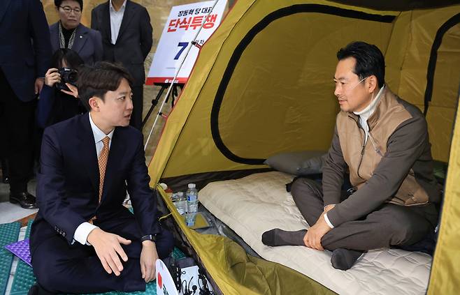 Jang Dong-hyeok, leader of the People Power Party, right, speaks with Lee Jun-seok, head of the Reform Party, who visited Jang’s hunger strike site in the National Assembly Rotunda Hall in Yeouido, Seoul, on Jan. 21. Jang marked the seventh day of his fast, demanding acceptance of a “dual special counsel” probe into the Unification Church and nomination donation allegations. [JOINT PRESS CORPS]