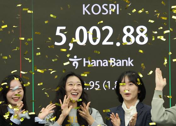 Korean bourse Kospi supasses the 5,000 mark for the first time on the morning of Jan. 22, 2026. Numbers are shown at a digital board in Hana Bank in Jung District, central Seoul, as dealers celebrate the historic moment. [YONHAP]
