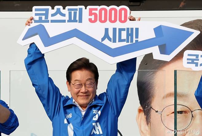 [서울=뉴시스] 조성우 기자 = 이재명 더불어민주당 대선후보가 29일 오후 서울 서초구 서울고속버스터미널광장에서 열린 유세에서 '코스피 5000 시대' 팻말을 들고 경제회복 퍼포먼스를 하고 있다. 2025.05.29. xconfind@newsis.com /사진=조성우