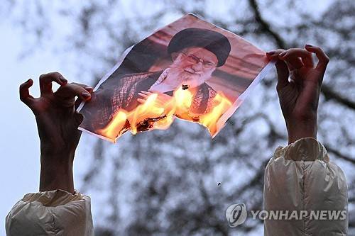 런던에서 열린 이란인 지지 시위 현장서 시위대가 하메네이 사진을 불태우고 있다. [로이터 연합뉴스 자료사진. 재판매 및 DB 금지]