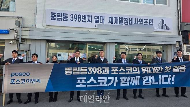 2025년 12월 4일 서울 중구 중림동 398번지 일대 재개발 조합 사무실 앞에서 포스코이앤씨 직원들이 현수막을 들고 기념촬영을 하고 있다. ⓒ데일리안 이수현 기자