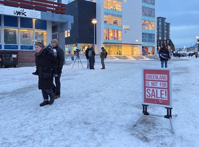 22일 그린란드 수도 누크에서 주민들이 '그린란드는 매매 대상이 아니다' 문구가 적힌 입간판 주변을 지나가고 있다. 누크=정승임 특파원