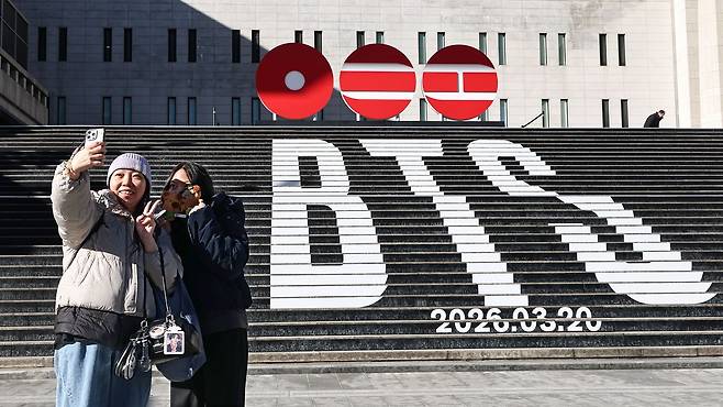 22일 서울 종로구 세종문화회관 계단에서 홍콩에서 온 관광객들이 오는 3월 3년 9개월 만에 '완전체'로 돌아오는 그룹 방탄소년단(BTS)의 컴백을 알리는 홍보물을 기념촬영하고 있다. 연합뉴스