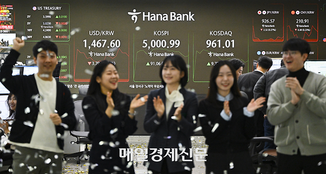 코스피가 장중 5000을 돌파한 지난 22일 서울 중구 하나은행 본점 딜링룸에서 딜러들이 코스피 5000시대 개막을 축하하며 퍼포먼스를 하고 있다.  [한주형기자]