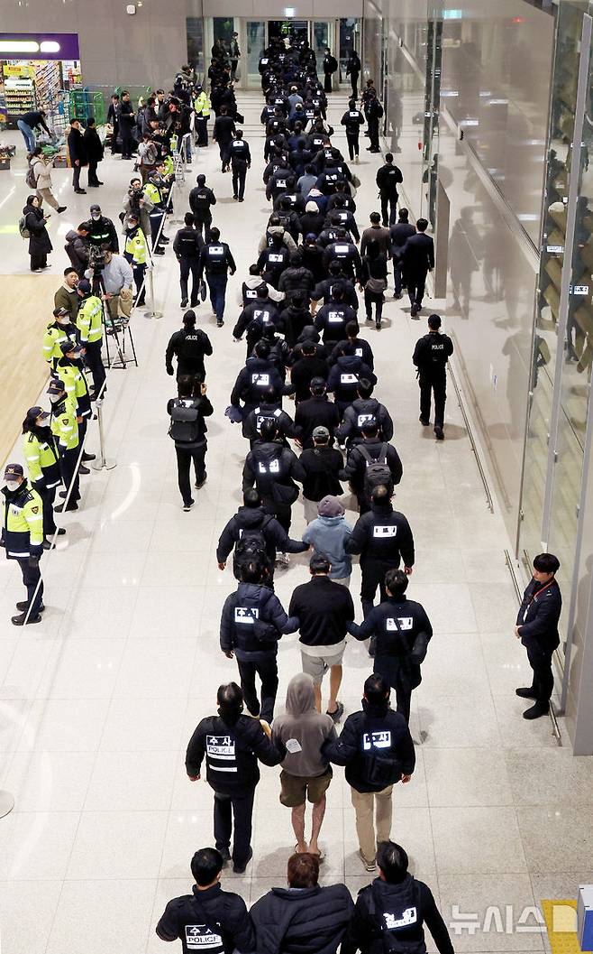 [인천공항=뉴시스] 김진아 기자 = 한국 국적 캄보디아 스캠조직 피의자들이 23일 오전 인천국제공항 제2터미널을 통해 강제 송환되고 있다.  초국가범죄 특별대응 TF는 캄보디아를 거점으로 우리 국민 869명에게 약 486억원을 편취한 한국 국적 피의자 73명을 강제 송환했다. 2026.01.23. bluesoda@newsis.com