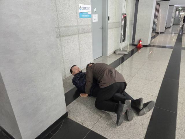 ▲기자회견 중 질문을 하든 시민단체 대표가 강제로 끌려 나가 브리핑룸 앞 복도에서 몸싸움을 하고 있는 모습. ⓒ독자제공