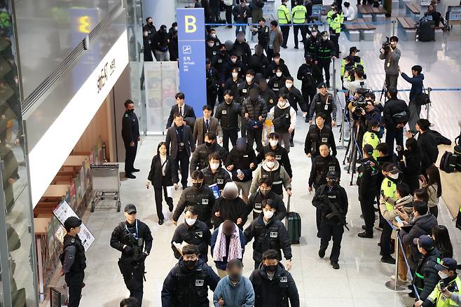 캄보디아에서 스캠(scam·사기), 인질강도 등 범행을 저지른 한국인 범죄 조직원들이 23일 인천국제공항을 통해 국내로 송환돼 수사기관으로 압송되고 있다. [연합]