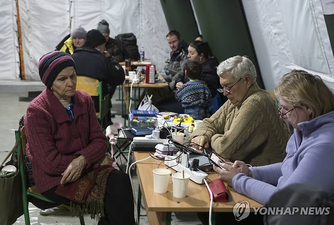 거리의 비상 대피 텐트에서 추위 피하며 스마트폰 충전하는 키이우 시민들 [EPA=연합뉴스]