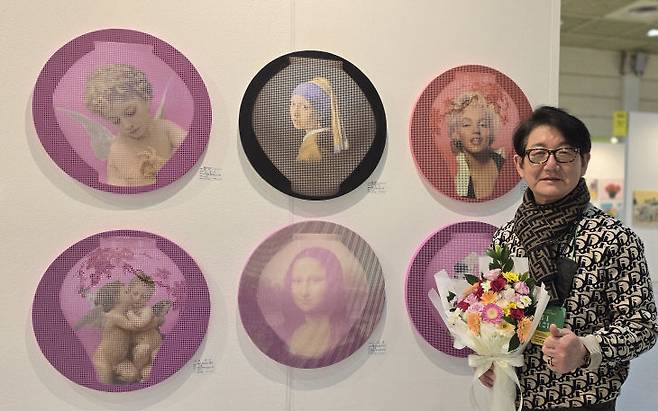 서울 코엑스 아트페스타에서 김중식 작가가 달항아리와 천사, 달항아리와 진주귀고리를 한 소녀, 달항아리와 마릴린 먼로, 달항아리와 모나리자 등 그의 작품들 앞에서 꽃다발을 들고  포즈를 취하고 있다.      사진 한성일 기자