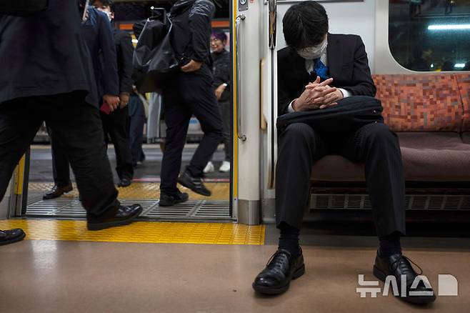 [도쿄=AP/뉴시스] 한 남성이 도쿄 지하철에서 잠을 청하고 있다. *기사 본문과는 무관한 사진. 2025.05.19.