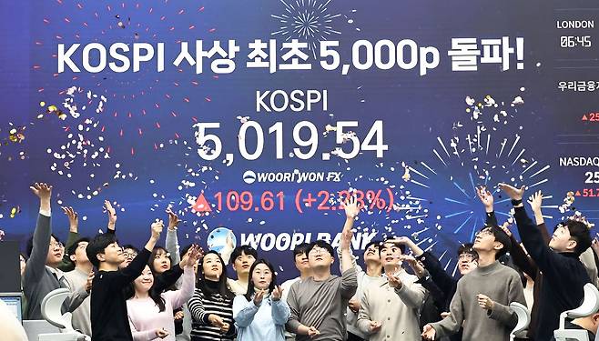 코스피 지수가 장중 사상 처음으로 5019.54를 기록한 22일 서울 중구 우리은행 본점 딜링룸에서 딜러들이 코스피 지수 5,000선 돌파를 축하하고 있다. 연합뉴스