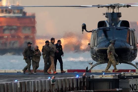 니콜라스 마두로 베네수엘라 대통령과 부인 실리아 플로레스가 5일(현지시간) 헬기에서 내린 뒤 호송 요원들에 이끌려 맨해튼의 남부연방지방법원으로 걸어가고 있다. 마약 관련 혐의 등으로 기소된 이들은 처음으로 미국 법정에 섰다. 로이터=연합뉴스