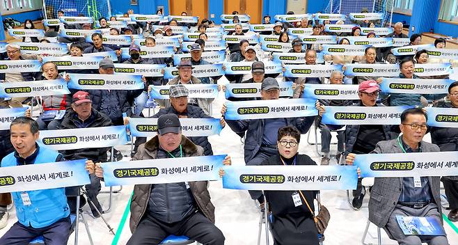 ▲ 지난해 11월 22일 오후 화성시 화수초등학교 강당에서 열린 '제1회 화성 서부 발전 세미나'에서 참석자들이 경기국제공항 유치 퍼포먼스를 하고 있다.