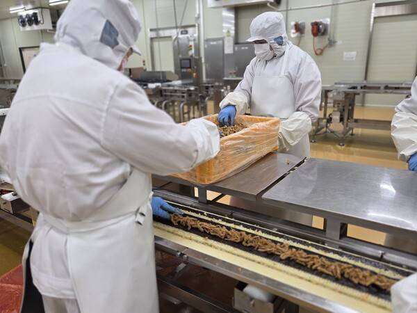 작업자들이 컨베이어벨트 위에 놓인 밥과 속김 위에 속재료를 일일이 올리고 있다 / 사진=정유진 기자