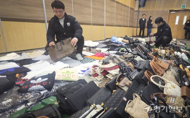 인천세관 관계자가 압수한 중국산 ‘짝퉁’ 위조 상품을 들어보이고 있다. 조병석기자