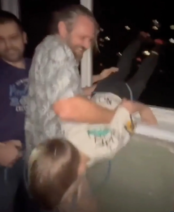 겁에 질린 아들을 7층 아파트로 다시 끌어올리며 웃고 있는 아버지. [East2West 화면 캡처]