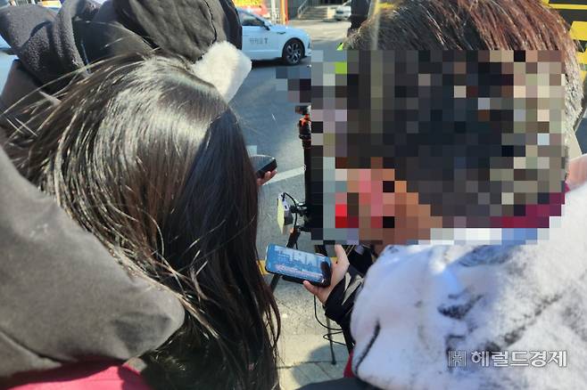 28일 오후 2시께 서울 서초구 서울중앙지방법원 별관 입구 앞에서 스마트폰으로 선고를 지켜보는 지지자들. 이영기 기자.