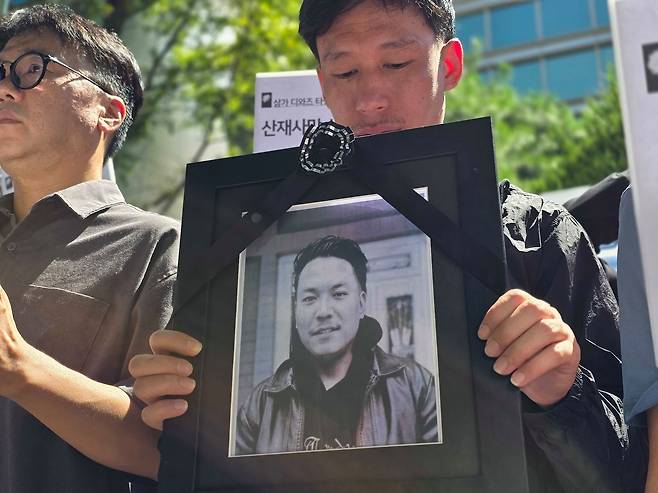 A coworker of Diaz Tamang, who dies in an industrial accident at a factory in Hwaseong, Gyeonggi in August 2025, holds Tamang’s portrait at a press conference. [LEE YOUNG-KEUN]