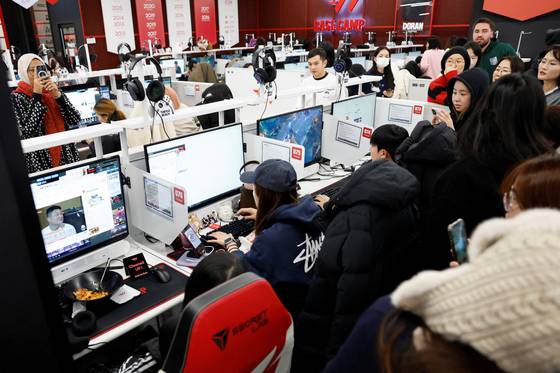 People gather behind a boy band BTS fan tries to book tickets for the group’s first concert in Korea in years at an internet cafe in Seoul on Jan. 22. [REUTERS/YONHAP]