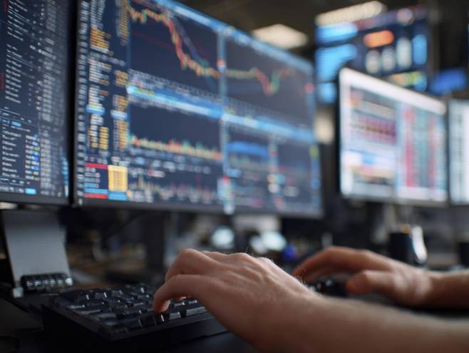 실시간 시세 화면과 거래를 실행하는 손은 환전 없이 원화로 매매할 수 있는 국내 레버리지 ETF 환경을 시각화한 이미지다. 접근성은 높아졌지만, 변동성과 수수료, 세금 구조라는 보이지 않는 비용이 여전히 투자 판단의 핵심 변수로 남아 있음을 암시한다. 게티이미지뱅크