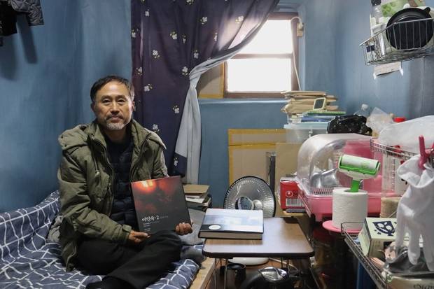 이강산 사진가가 달방에서 ‘여인숙·2’ 사진집을 들어보이고 있다. 김수호 기자