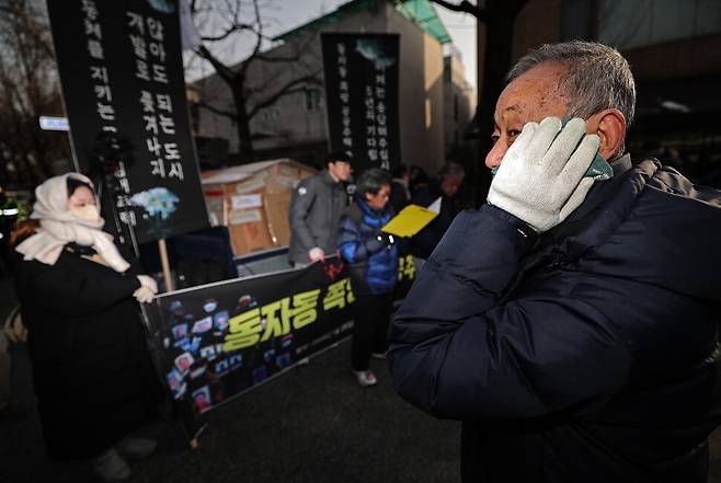 한 동자동 주민이 청와대 들머리에서 열린 ‘동자동 쪽방 공공주택 촉구 결의대회’에서 추운 듯 핫팩으로 얼굴을 비비고 있다.