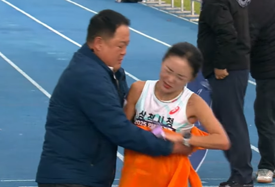 지난달 23일 인천 송도에서 열린 '2025 인천국제마라톤' 여자 국내부 경기에서 1위로 골인한 삼척시청의 이수민(오른쪽) 선수가 결승선을 통과한 직후의 모습. 수건을 두르며 잡아주는 김완기 감독을 뿌리치고 있다. KBS스포츠 유튜브 영상 캡처