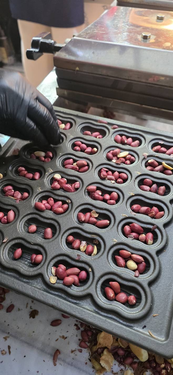 서문시장 내 땅콩빵집 점원이 반죽을 붓기 전 빠른 손놀림으로 미리 준비해 둔 빵틀에 땅콩을 넣고 있다. 땅콩빵 개당 들어가는 땅콩 갯수는 대충 봐서는 가늠이 되지 않을 정도로 많다. 김지혜기자