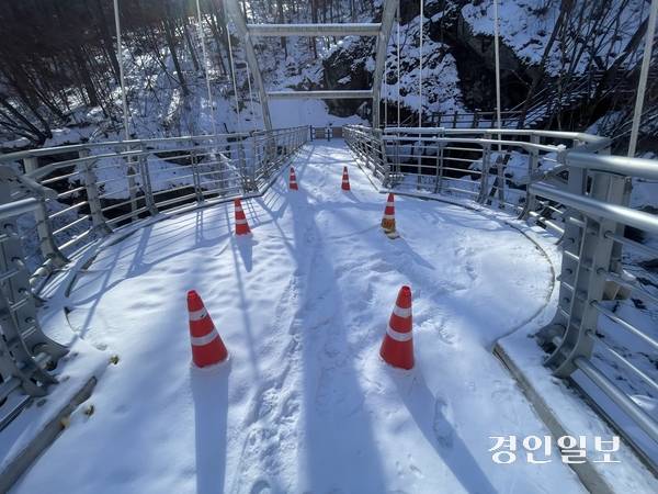 가평 명지산군립공원 등산로 입구에서 1.2㎞ 떨어진 곳에 조성된 아치교 ‘구름다리’에 눈이 쌓여 있는 가운데 다리 중간 부근에 라바콘이 설치돼 있다. 가평/김민수기자 kms@kyeongin.com