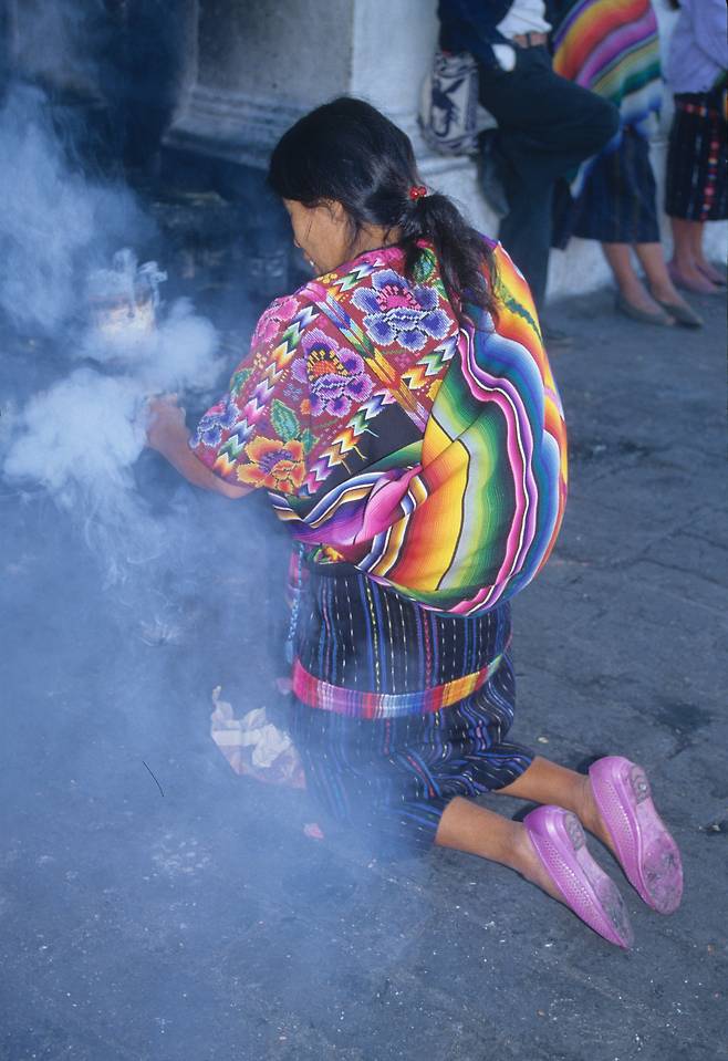 과테말라 치치카스테낭고의 교회 앞마당에서 연기를 피우며 기도하는 인디오 여인.