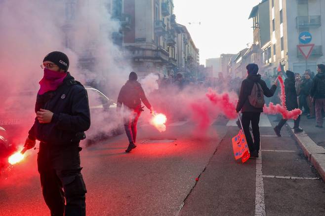2월 7일 오후(현지 시각) 이탈리아 밀라노에서  '지속 불가능한 올림픽 위원회'가 주최한 올림픽 반대 집회에서 시위대가 붉은 연기를 피우며 시위를 하고 있다. 이번 집회에는 그린피스 등 단체가 연합해 밀라노 메달리에 도로(piazza medaglie d'oro)에서 시작해 시내 곳곳을 행진한 뒤 코르베토역 인근 도로에서 홍염을 피우며 경찰 차벽을 향해 불꽃과 벽돌 그리고 유리병을 던졌다. / 밀라노=장련성 기자