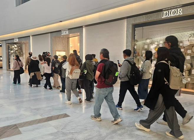 지난 5일 ‘K컬처 환승투어’ 신청자들이 더현대 서울 1층 명품매장 앞을 지나고 있다. [김진 기자]