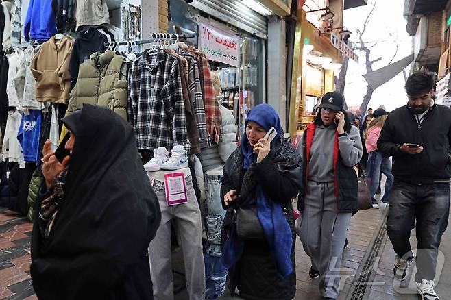 2026년 1월 28일, 이란 테헤란 타지리시 바자르에서 사람들이 휴대전화를 사용하며 거리를 걷고 있다. ⓒ AFP=뉴스1
