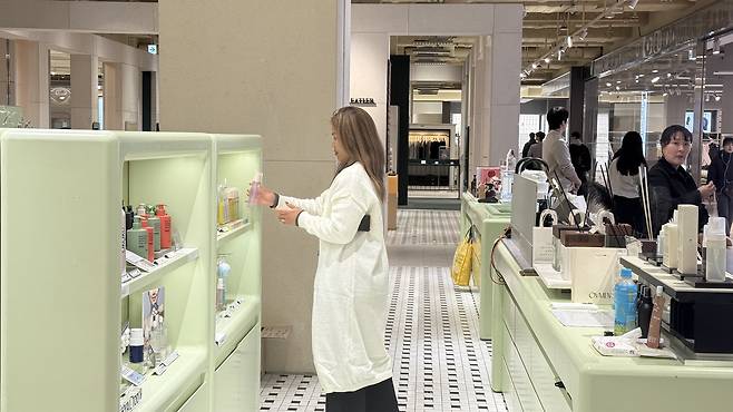 A participant of K-culture Transit Tour browses different hair products at The Hyundai Seoul on Feb.5. [WOO JI-WON]