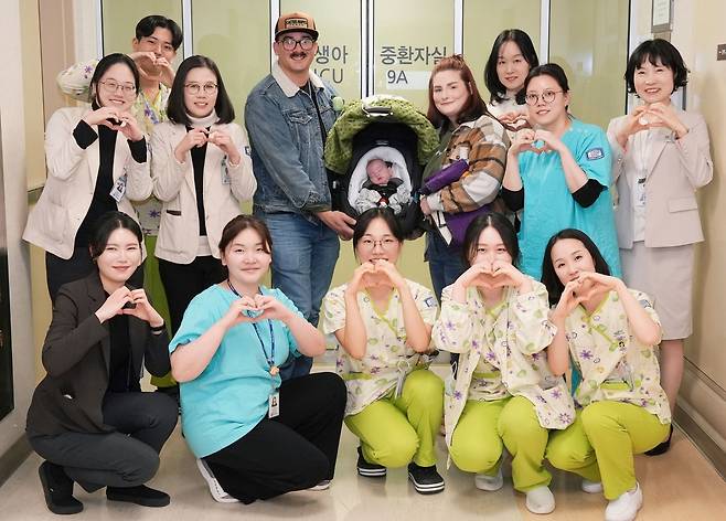 서울성모병원에서 임신 6개월에 조기 분만으로 태어나 출생체중 688g에 불과했던 초극소 미숙아 스텟슨(Stetson) 가족이 퇴원을 기념하며 의료진과 기념사진을 촬영하고 있다. 사진은 강병수(뒷줄 왼쪽부터) 산부인과 교수, 주치의 김세연 소아청소년과 교수, 스텟슨 가족, 이지연(뒷줄 오른쪽) 국제진료센터장.   [서울성모병원 제공]