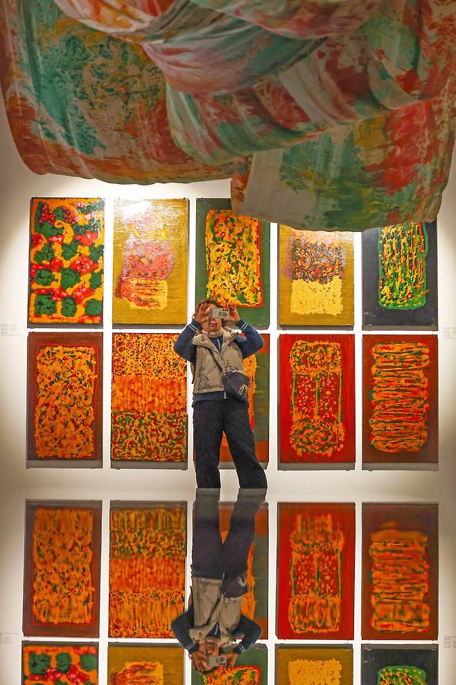 성파 스님 전시장엔 작품에서 배어나온 옻 향기가 그윽하다. 성파스님의 전시회 개막 후 관람객이 천장에 걸린 옻칠 염색 작품과 벽에 걸린 옻칠 회화 작품을 감상하고 사진을 촬영하고 있다. /장경식 기자